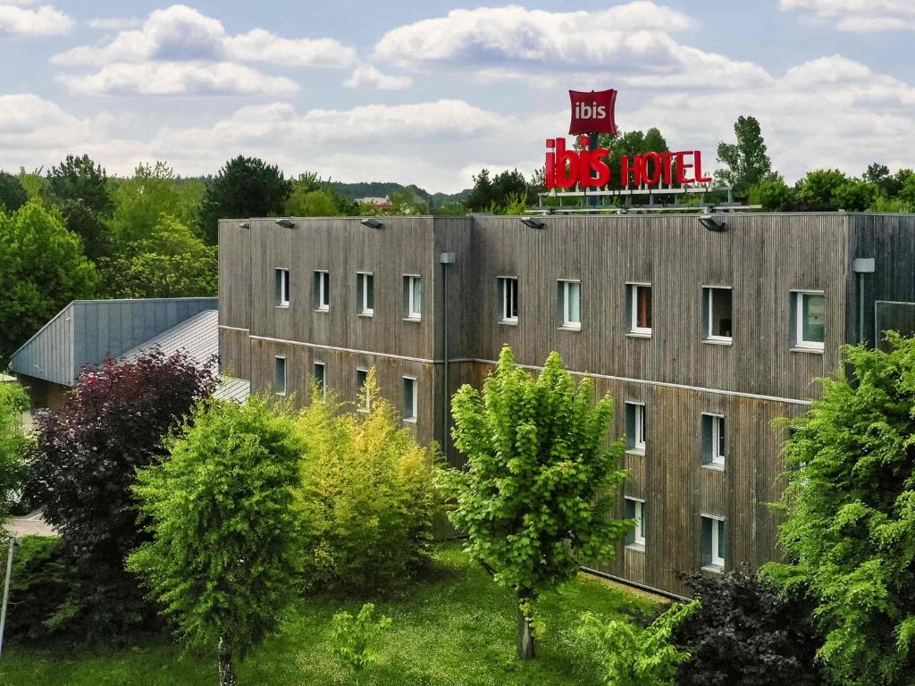 a building with a red sign on top of it at ibis Nemours in Nemours