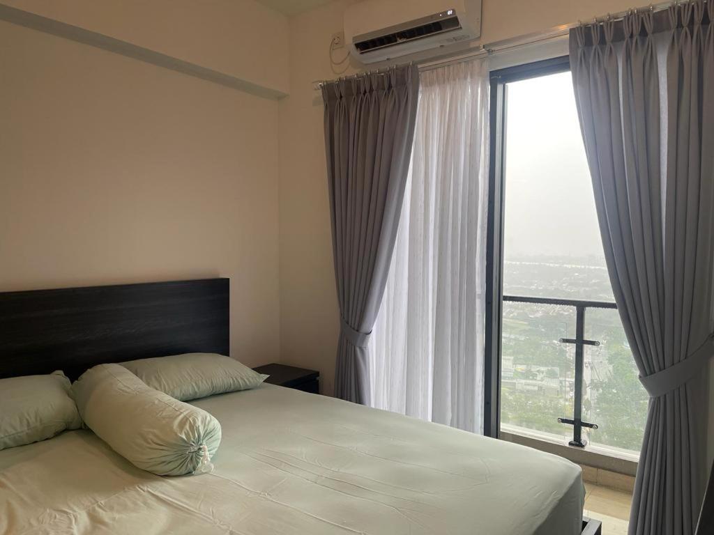 a bedroom with a bed and a large window at APARTEMEN SKY HOUSE BSD in Samporo