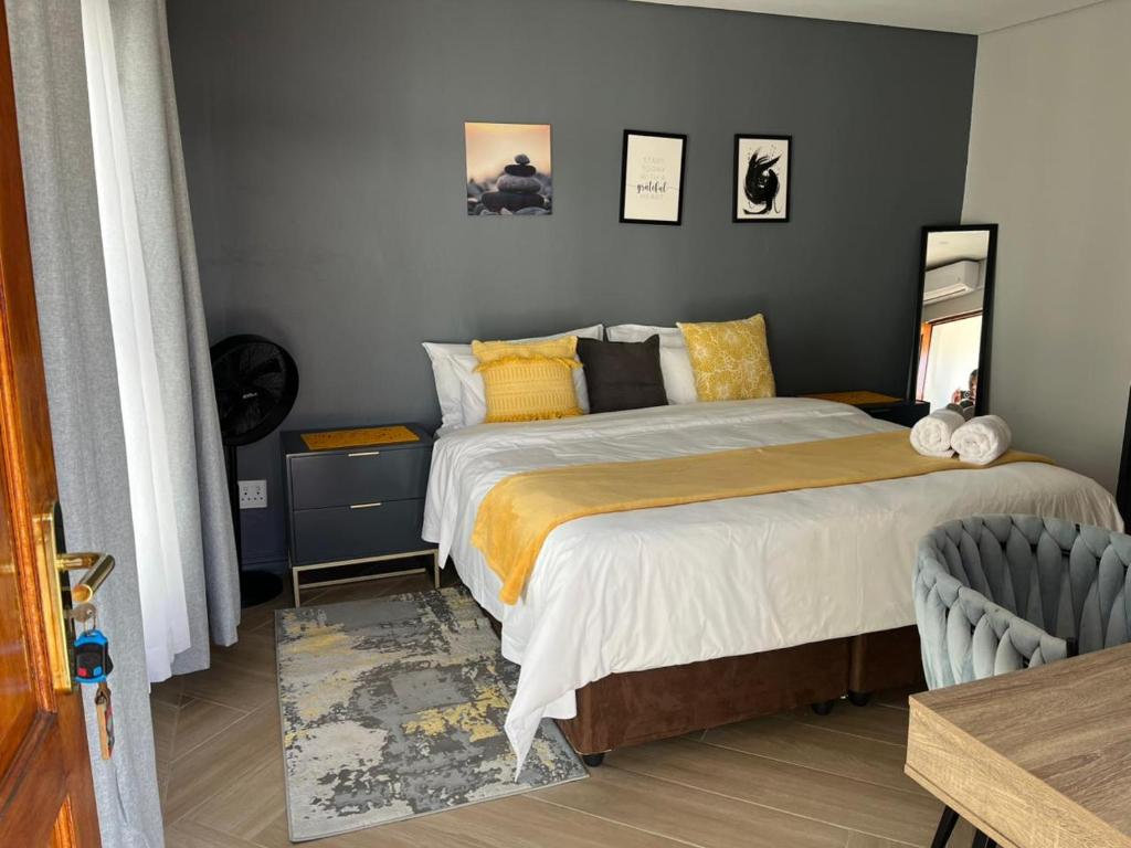 a bedroom with a bed with yellow and black pillows at Black Villa Lodge in Hammanskraal