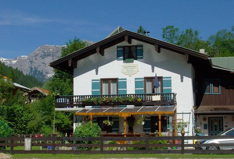 a large white house with a balcony and a car at Haus Auerhahn Ferienwohnungen in Ramsau