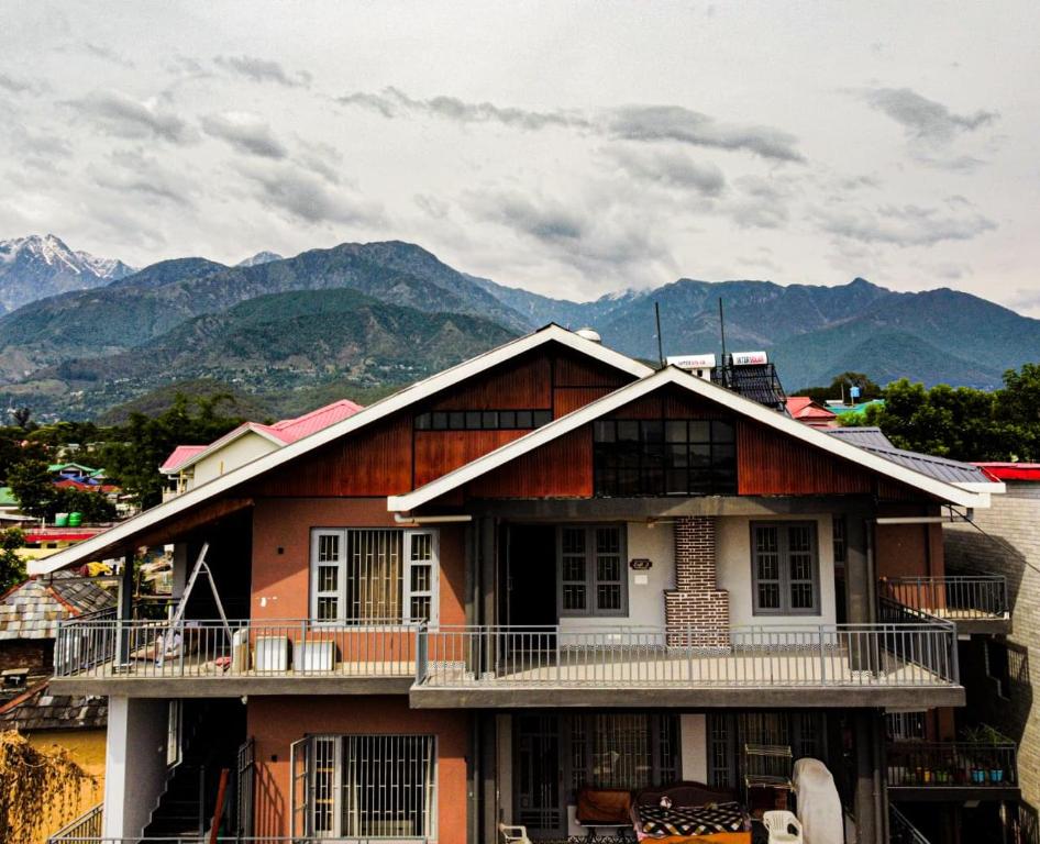 a house with a balcony and mountains in the background at Lofted Peaks in Pālampur