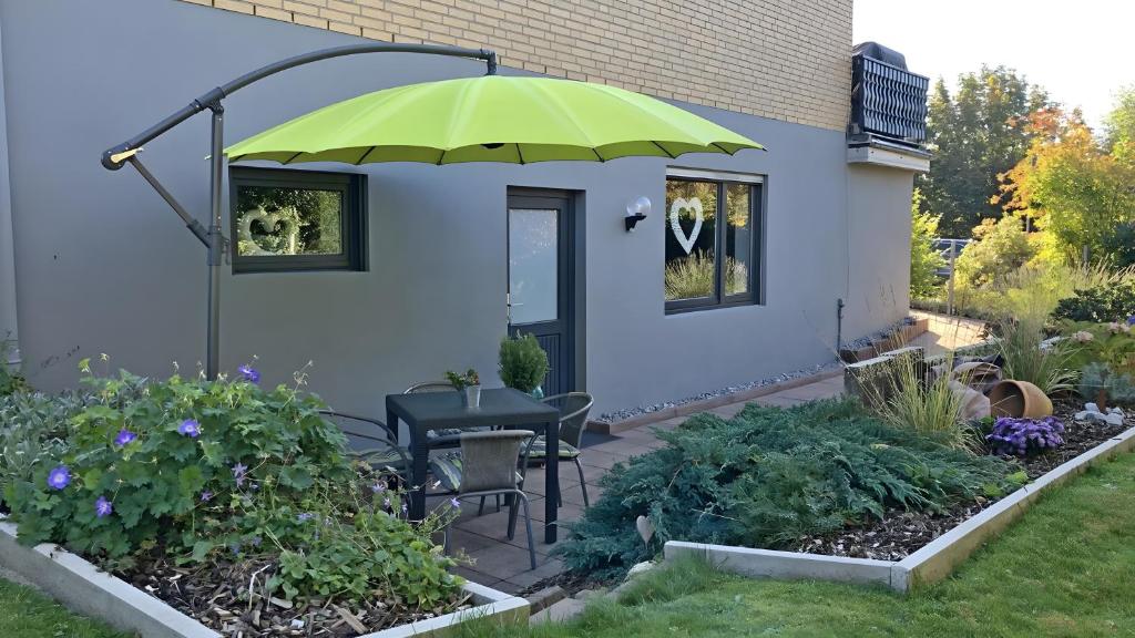a patio with a table and a green umbrella at Fewo Carpe Diem in Scheuerfeld