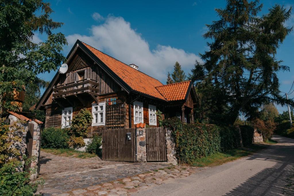 a small wooden house with a red roof at Aparte Mazury Jaśkowo in Jaśkowo