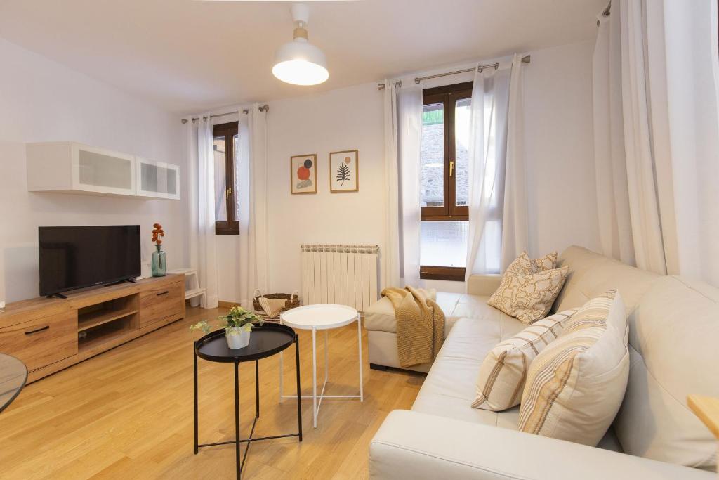 a living room with a white couch and a tv at Calma by BeValle in Panticosa