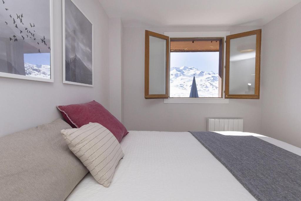 a bedroom with a bed and two windows at La Ventana de Formigal by BeValle in Formigal