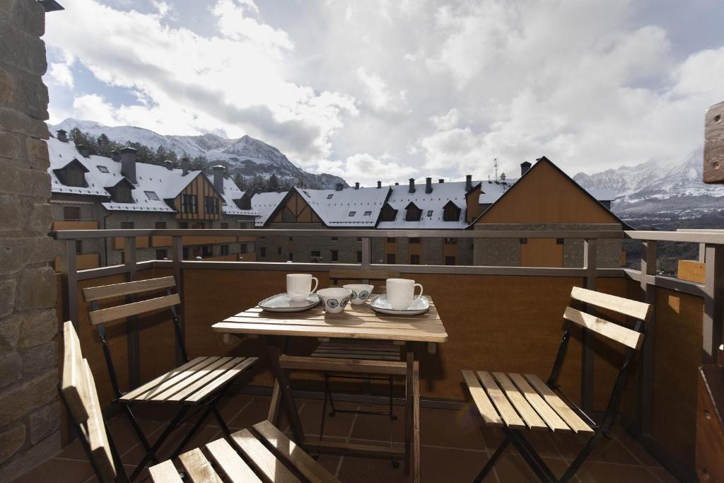 a table and chairs on a balcony with a view at CuMbre del Sarrio by BeValle in Panticosa