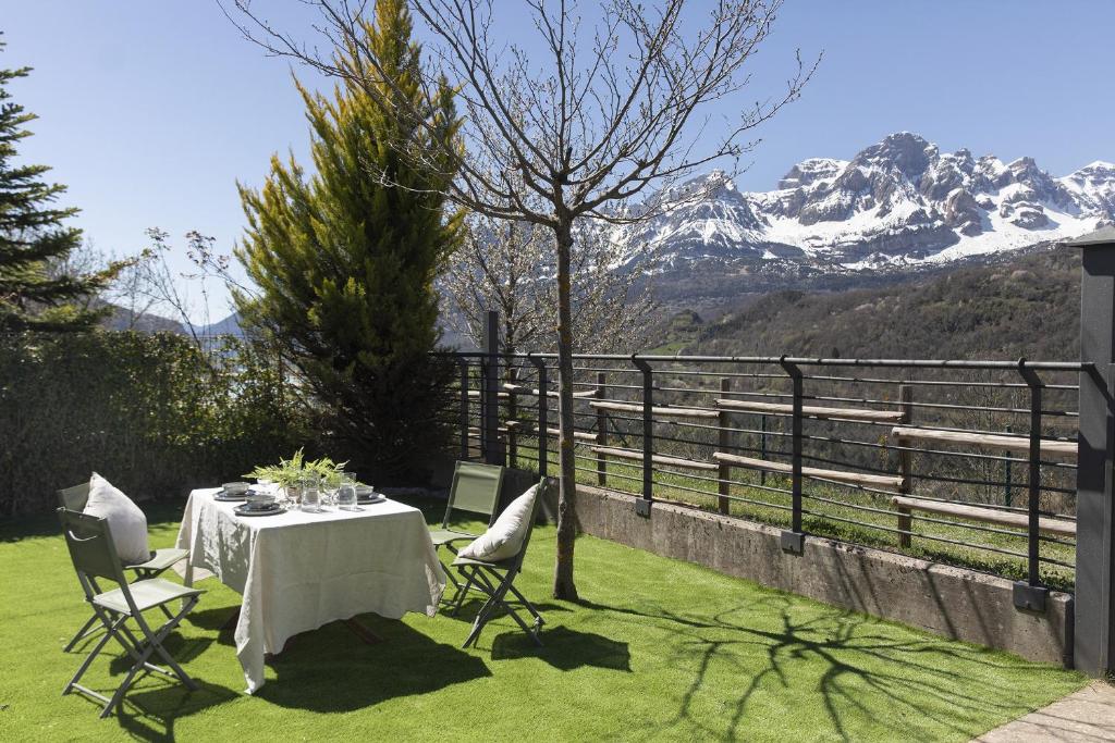 a table and chairs on the grass with a mountain at El Mirador by BeValle in Panticosa