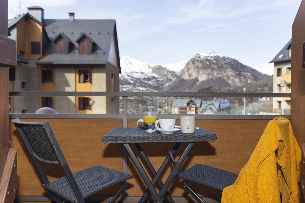 a table and chairs on a balcony with mountains at Senda by BeValle in Panticosa