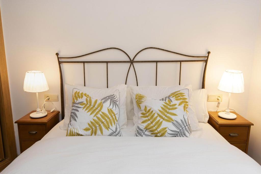 a bedroom with a white bed with pillows and two lamps at Rincón del Pueyo by BeValle in El Pueyo de Jaca