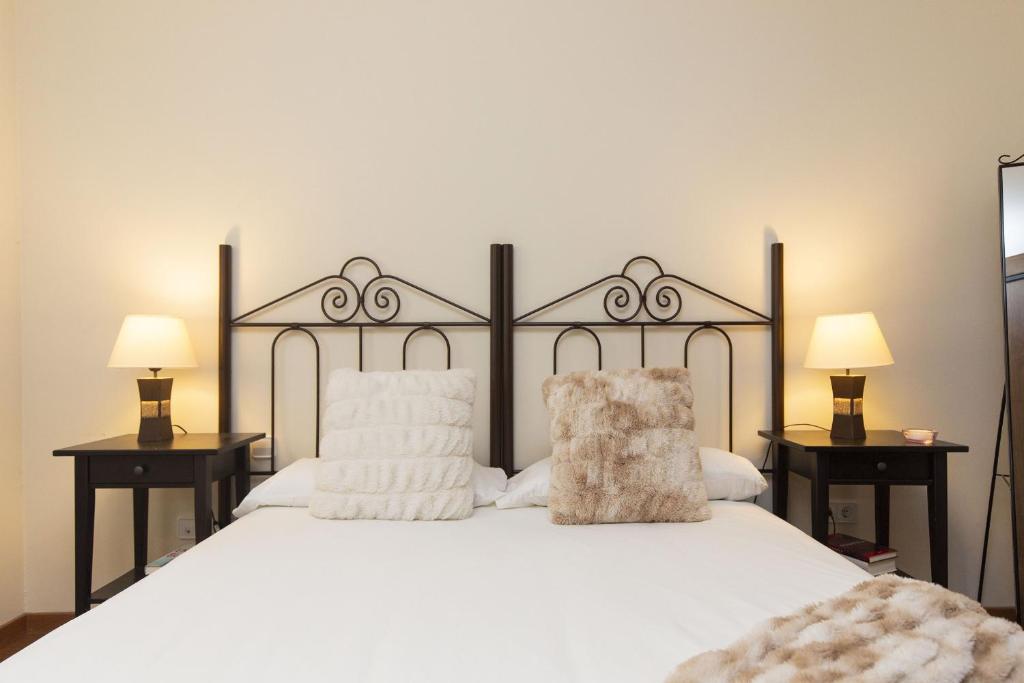 a bedroom with a large white bed with two lamps at Pirenaica by BeValle in Escarrilla