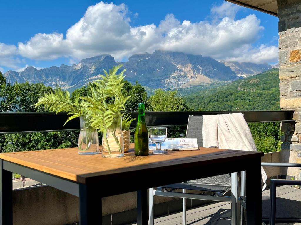 a table with a bottle of wine on a balcony with mountains at Casa BellaVista by BeValle in Panticosa
