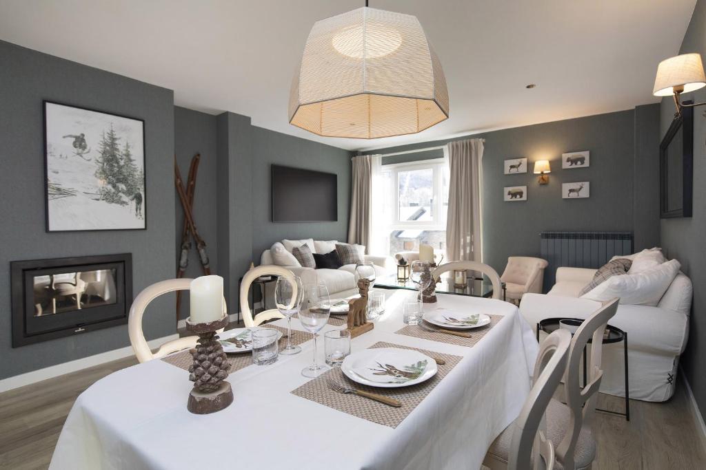 a dining room and living room with a white table and chairs at El Ciervo de Santa María by BeValle in Panticosa
