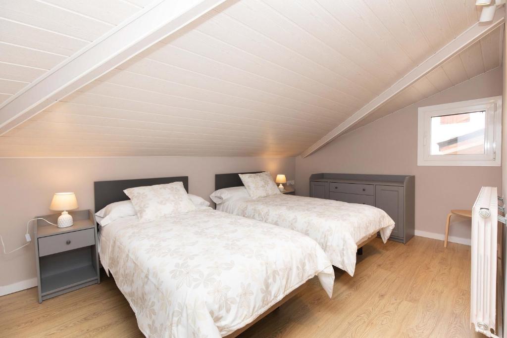 a attic bedroom with two beds and a window at Ático del Prado by BeValle in Sallent de Gállego