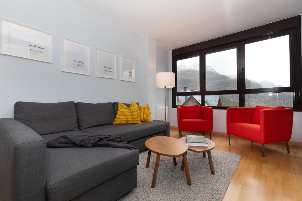 a living room with a gray couch and two red chairs at Narnia by BeValle in Panticosa