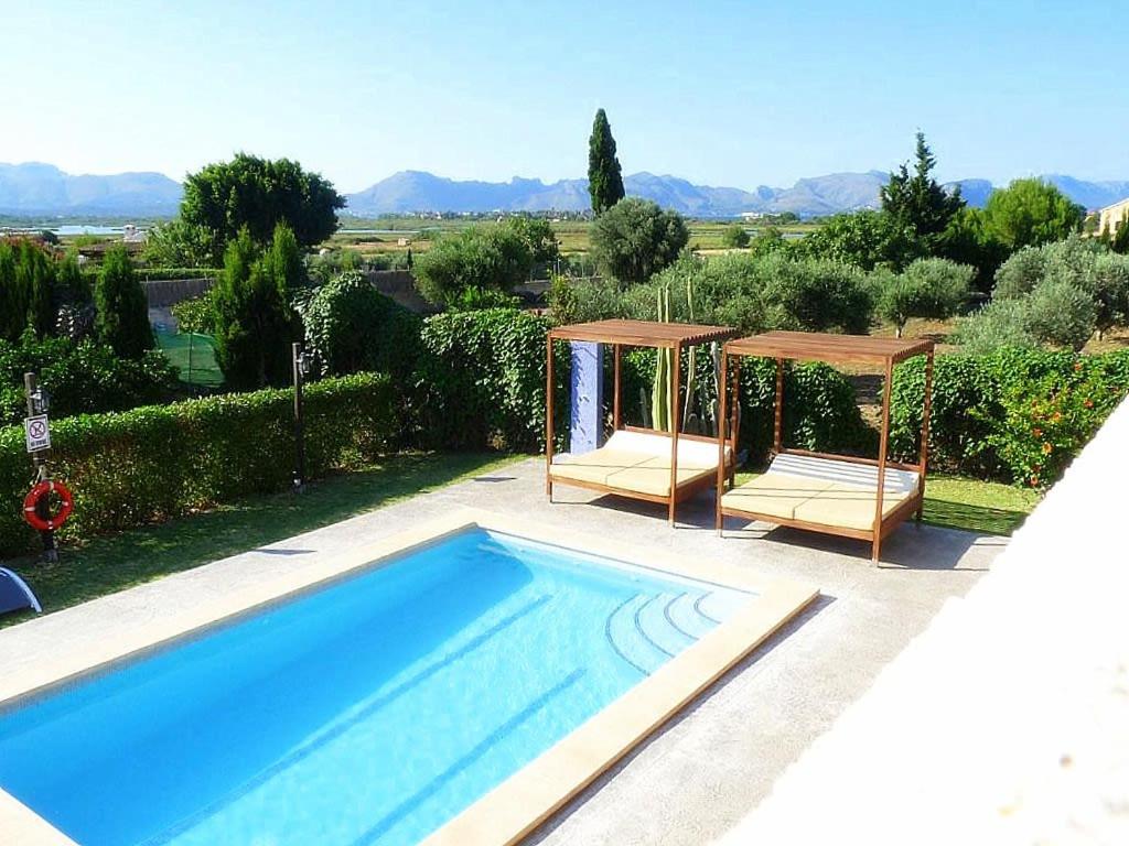 a swimming pool with two chairs and a gazebo at Villa Son Fanals in Alcudia