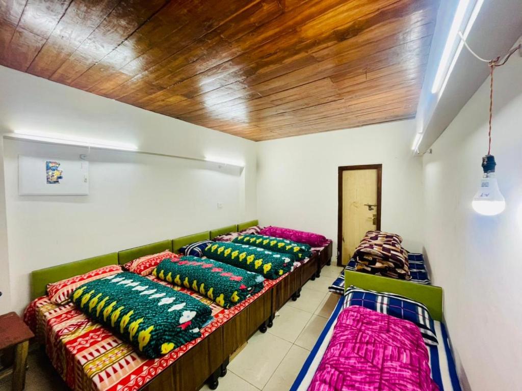 a room with four beds with colorful pillows on them at Kedarnath Aastha Path ME5 Building in Kedārnāth