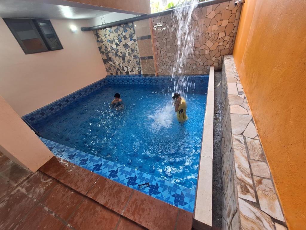 two people in a swimming pool with a waterfall at Galaxy Villa Tam Đảo in Tam Ðảo