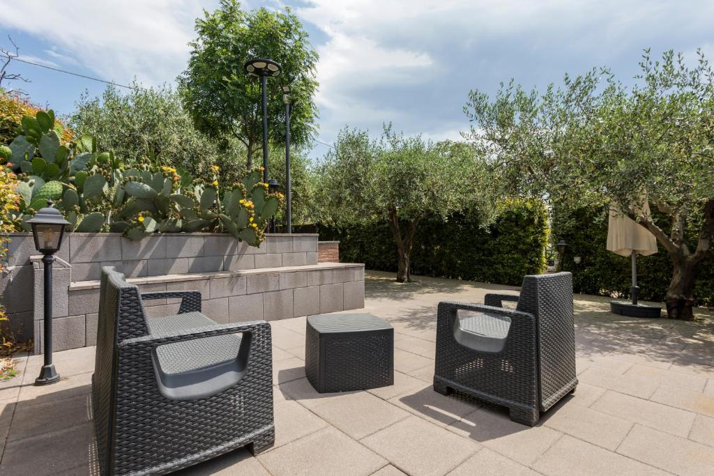 two wicker chairs and a bench in a park at Casetta delle Rose sull'etna in Viagrande