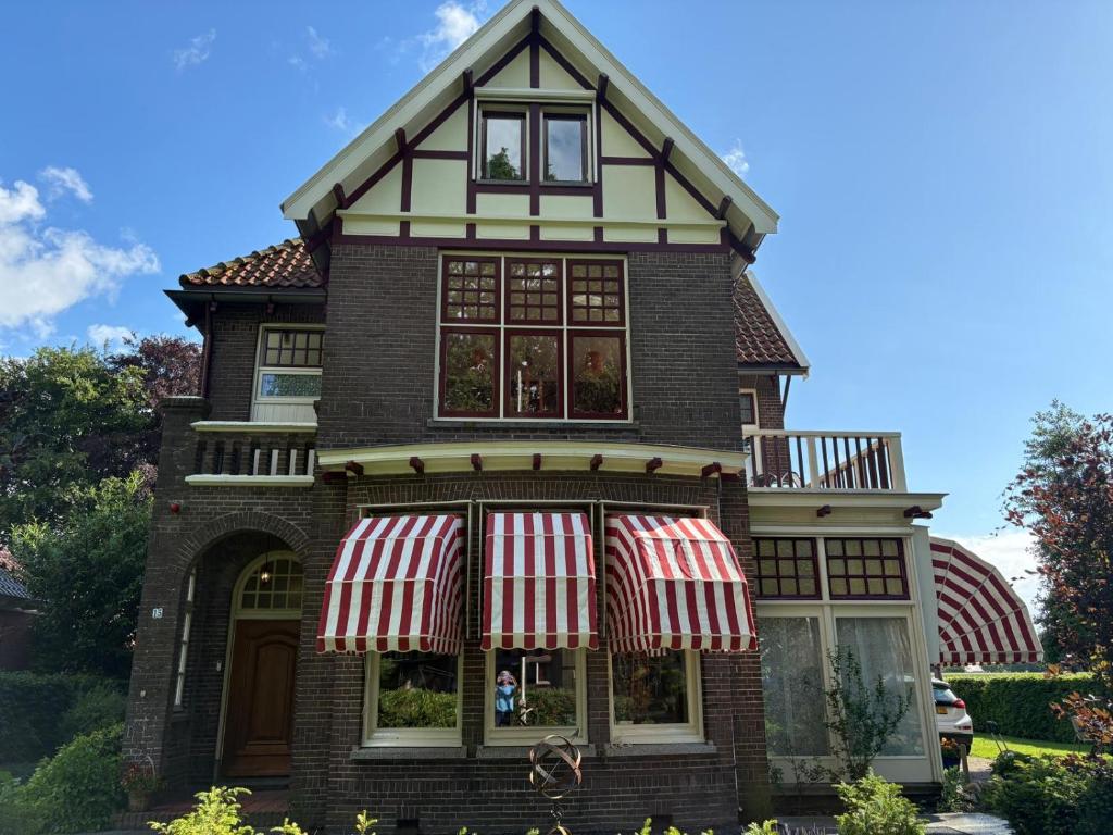 a house with red and white awnings on it at Burgers & Buitenlui in Diever