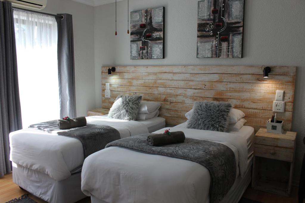 a room with two beds and a window at Villa Mariss Guesthouse in Kraaifontein
