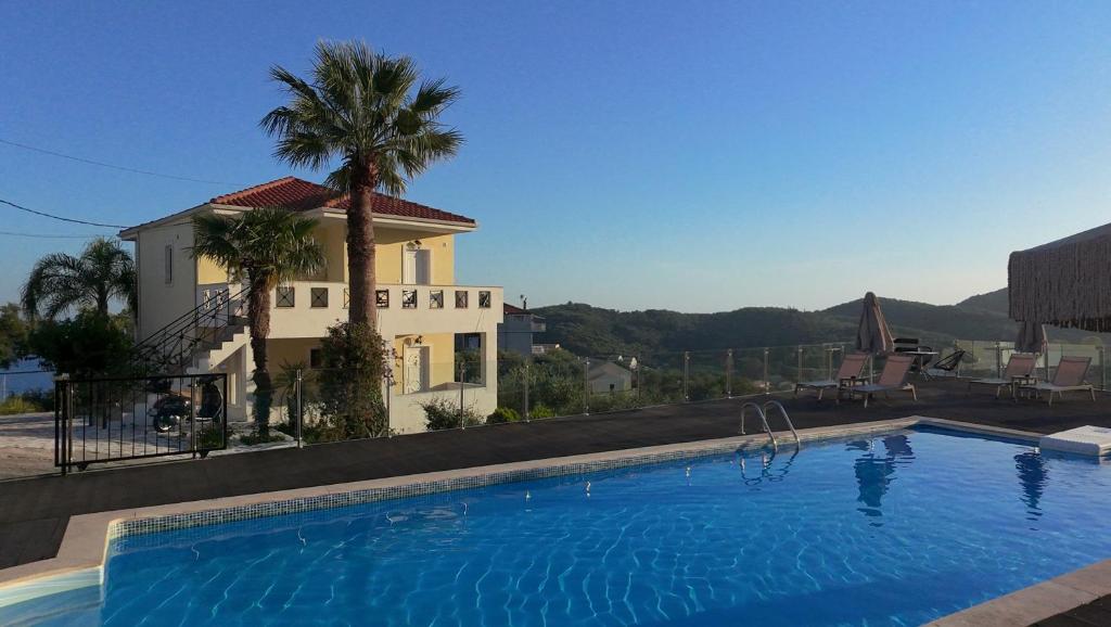 a swimming pool in front of a house with a palm tree at Diogenis Parga Studios in Parga