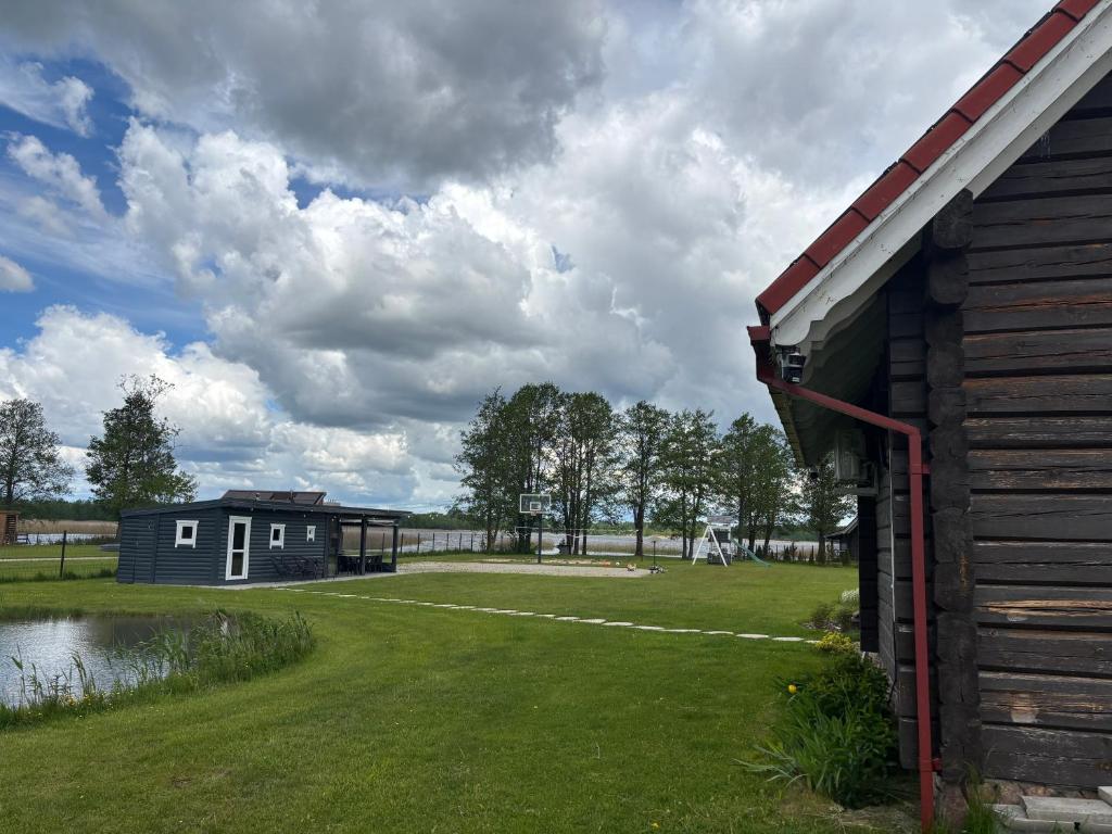 a barn and a house in a field with a pond at Šarkos sodyba in Miežonys