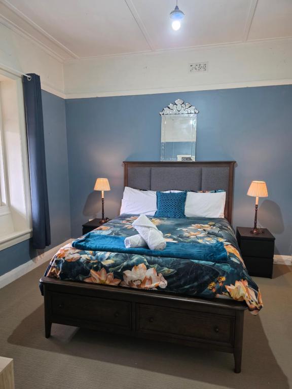 a bedroom with a large bed with blue walls at The Red Manor on Mort in Lithgow