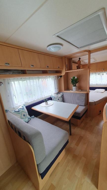 a room with a table and a couch in a boat at Brigga Camping Mietwohnwagen in Ritzingen