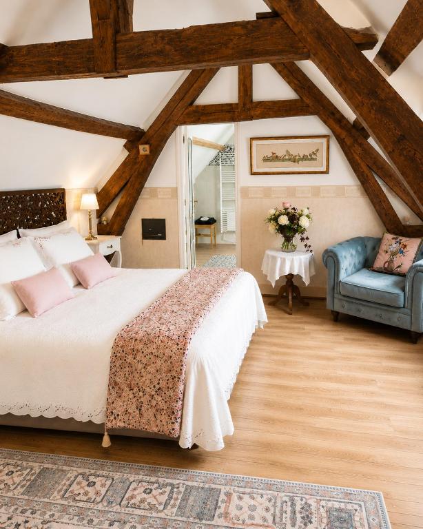 a bedroom with a bed and a blue chair at Les oiseaux de passage - chambre d hôtes, paisible in Gaillon