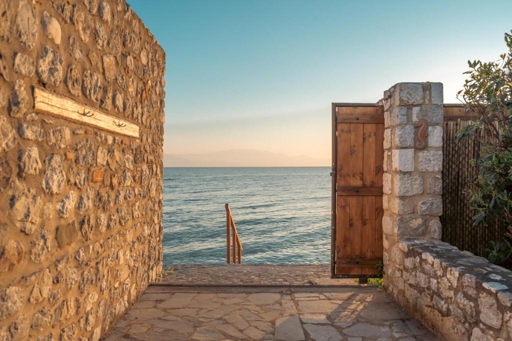 an open door to the ocean behind a stone wall at IoMi Terra & Mare in Eleonas