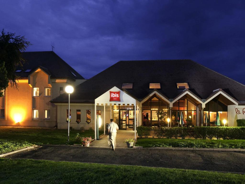 a man walking in front of a store at night at Ibis Provins in Provins