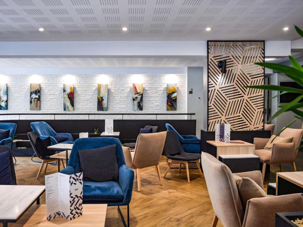 a waiting room with blue chairs and tables at Mercure Lorient Centre in Lorient
