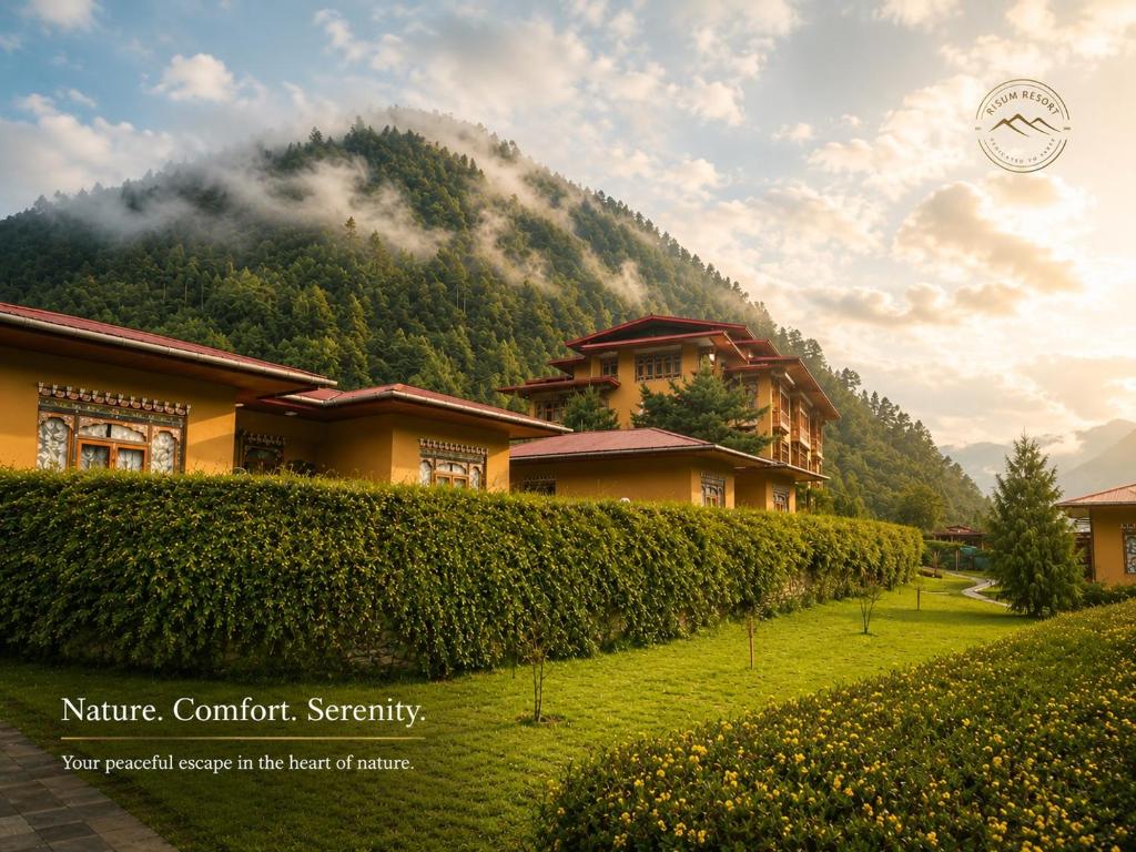 a house in front of a mountain with a hedge at Risum Resort in Ha