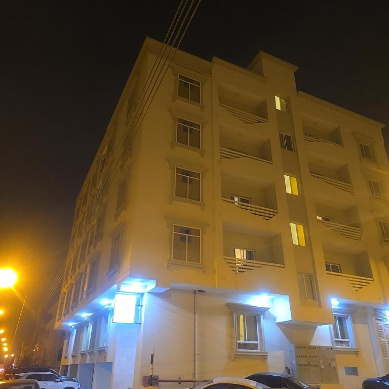 a tall white building with lights on it at night at Golden Seasons Rose in Salalah