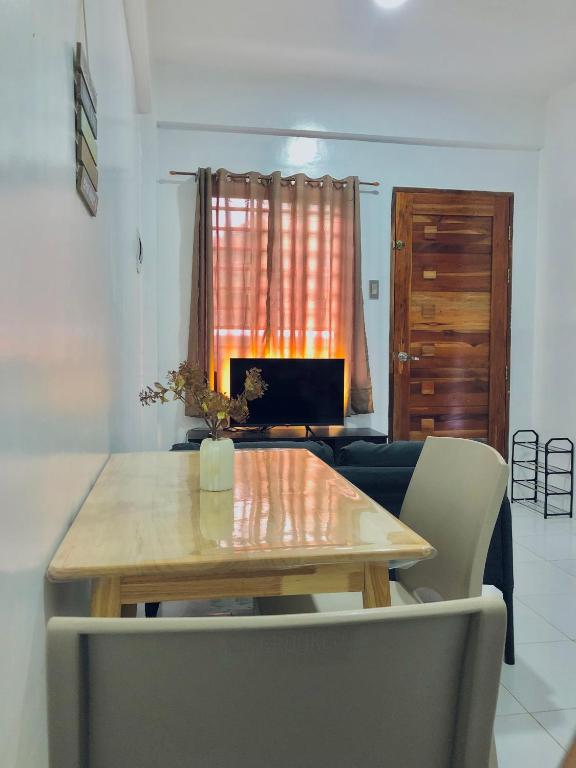 a dining room table with a couch and a laptop at Reinhardshausen Suites and Residences- Lovely Air-Conditioned Units in Tuguegarao City