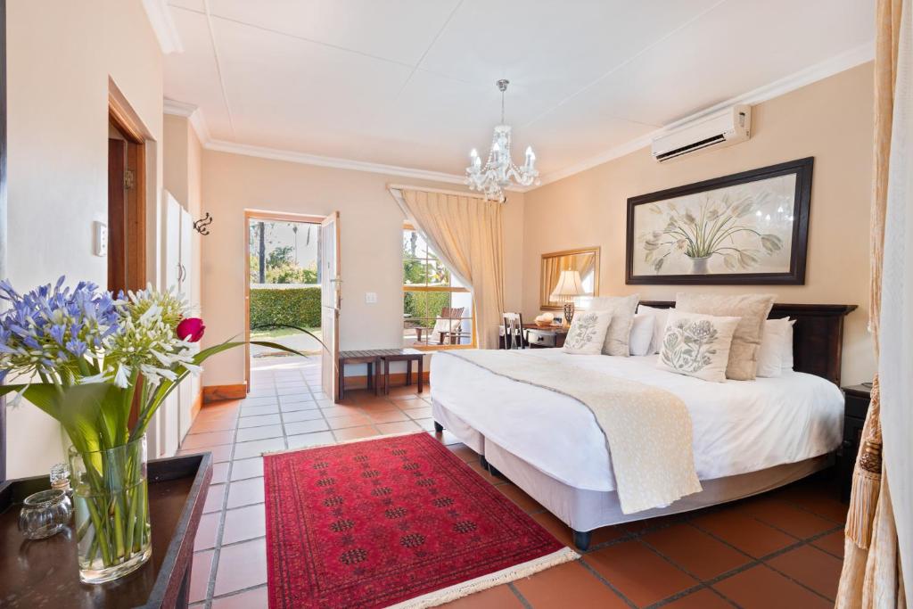 a bedroom with a white bed and a red rug at Oue Werf Country House in Oudtshoorn