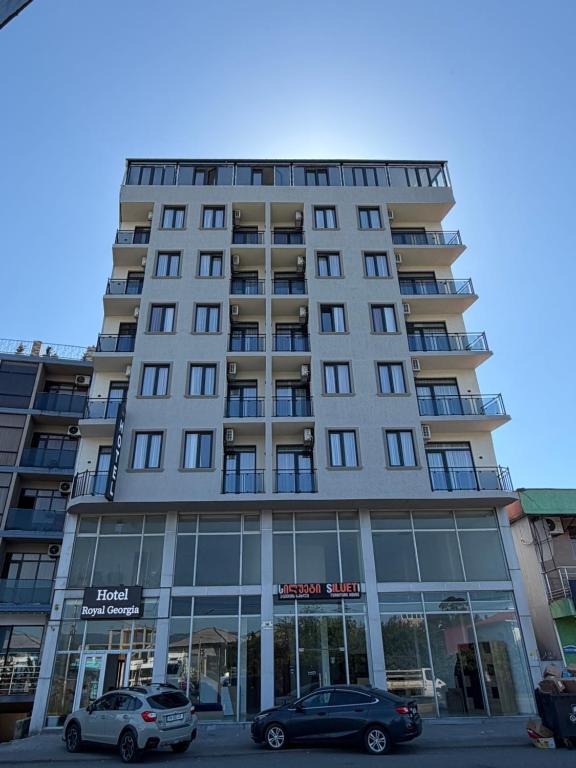 a tall building with cars parked in front of it at Hotel Royal Georgia 2 in Batumi