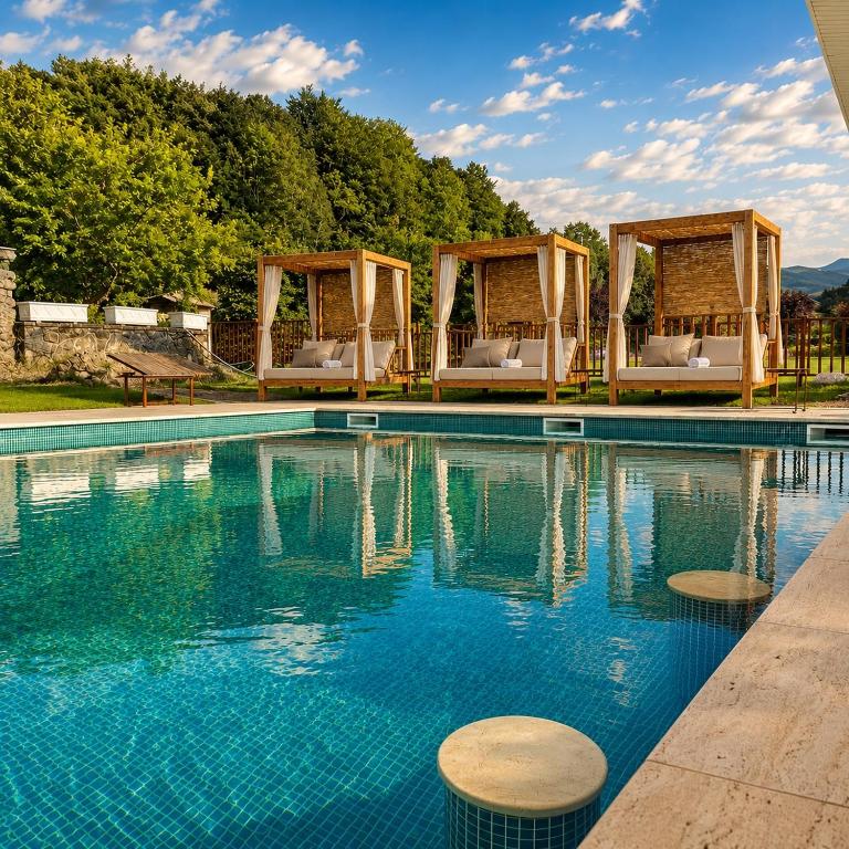 a swimming pool with two gazebos at ELS OCELLS Apartaments i Cases Rurals in Camprodon