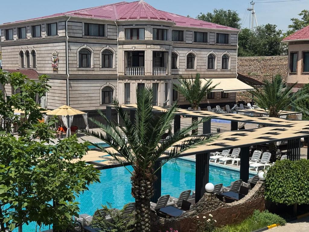 a hotel with a swimming pool and a building at Edem Hotel Shymkent in Shymkent