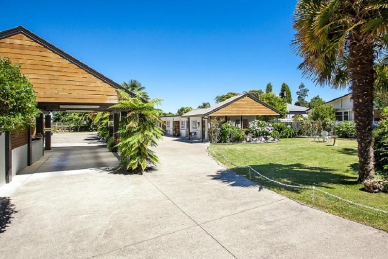 een oprit naar een huis met palmbomen bij Amber Court Motel in Whakatane