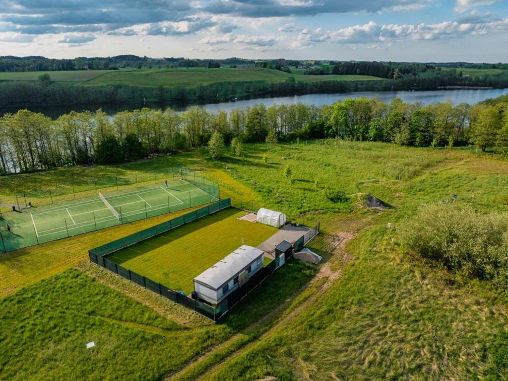 an aerial view of a house in a field with a tennis court at Holenderka nad Szelmentem in Jeleniewo
