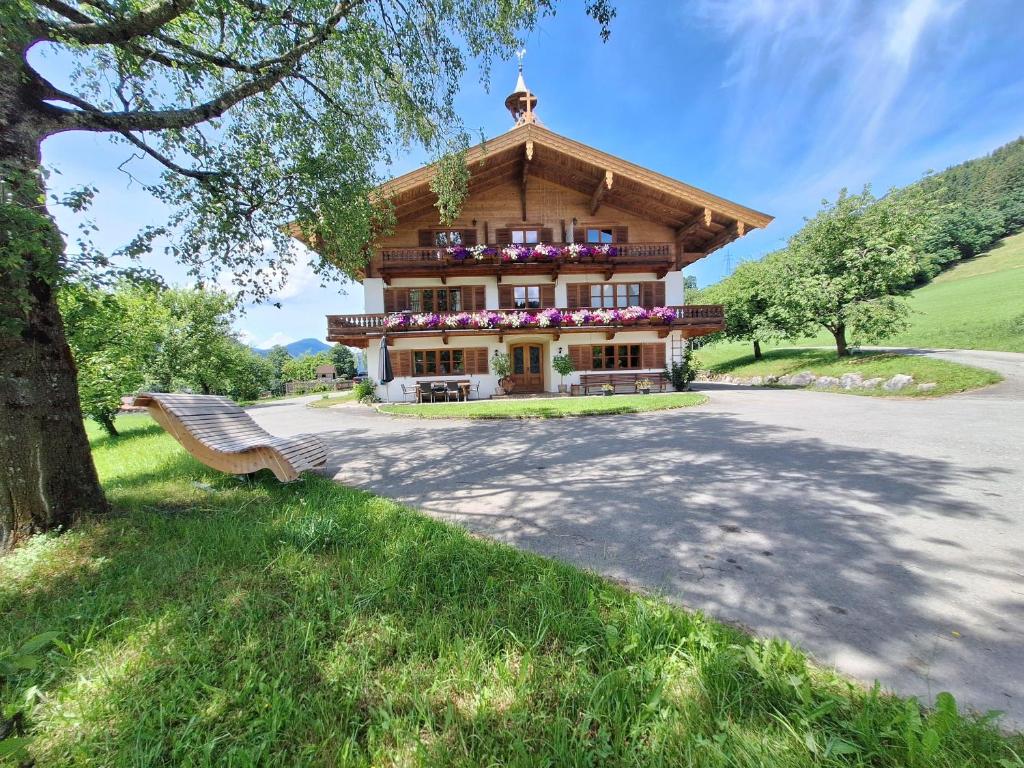 a house in the mountains with a bench in front of it at Winklern Appartment Wildschütz in Kitzbühel