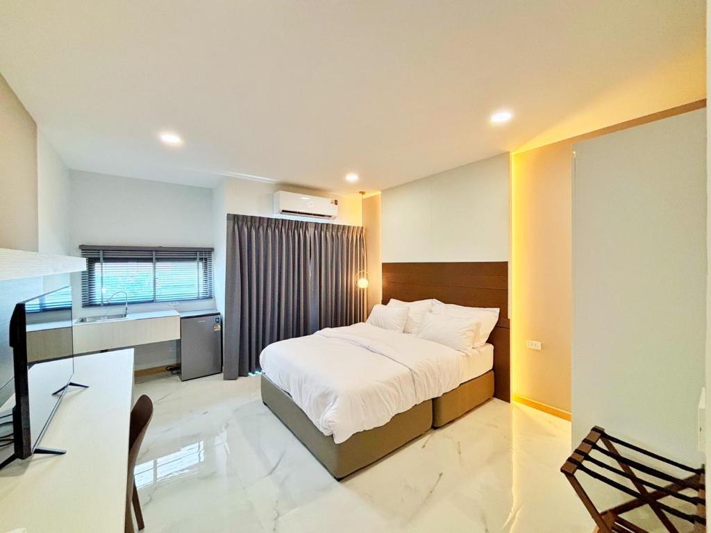 a bedroom with a bed and a desk in it at Jaroon House in Samutprakarn
