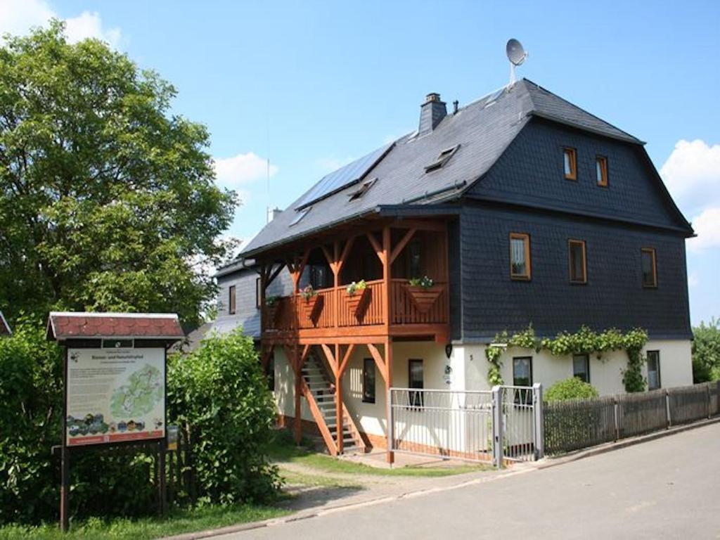 a large black and white house with a balcony at Ferienwohnungen Am Nussbaum in Saalfeld