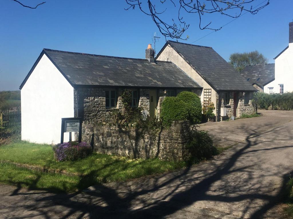 an old stone building on the side of a road at Moorshead Farm Cottages in Llysworney