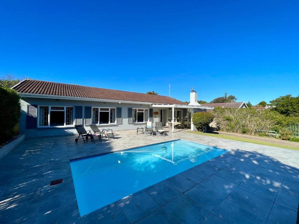 a swimming pool in front of a house at Beach House on Pachena in Plettenberg Bay