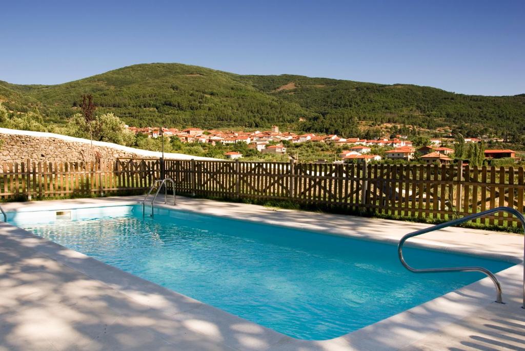a swimming pool with a fence and mountains in the background at Hotel Conventual Sierra de Gata in San Martín de Trevejo