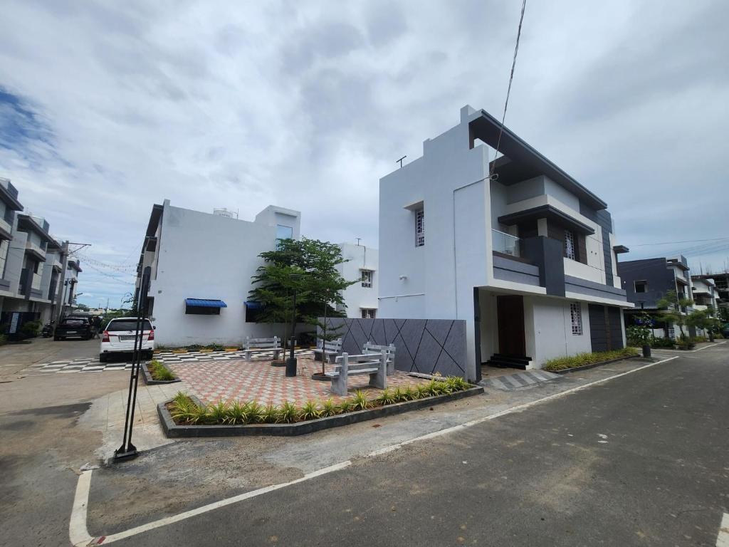 a white building on the side of a street at Holiday Home Madurai - Duplex Villa Umachikulam in Madurai
