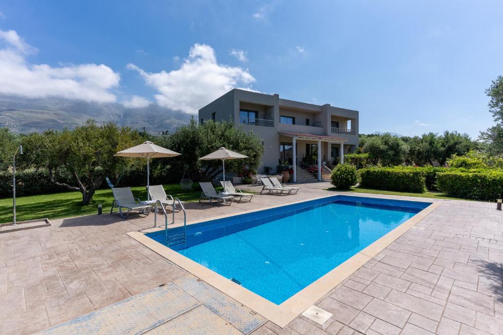 a villa with a swimming pool and a house at Kassiani Studios Olive Groove hotel in Plakias