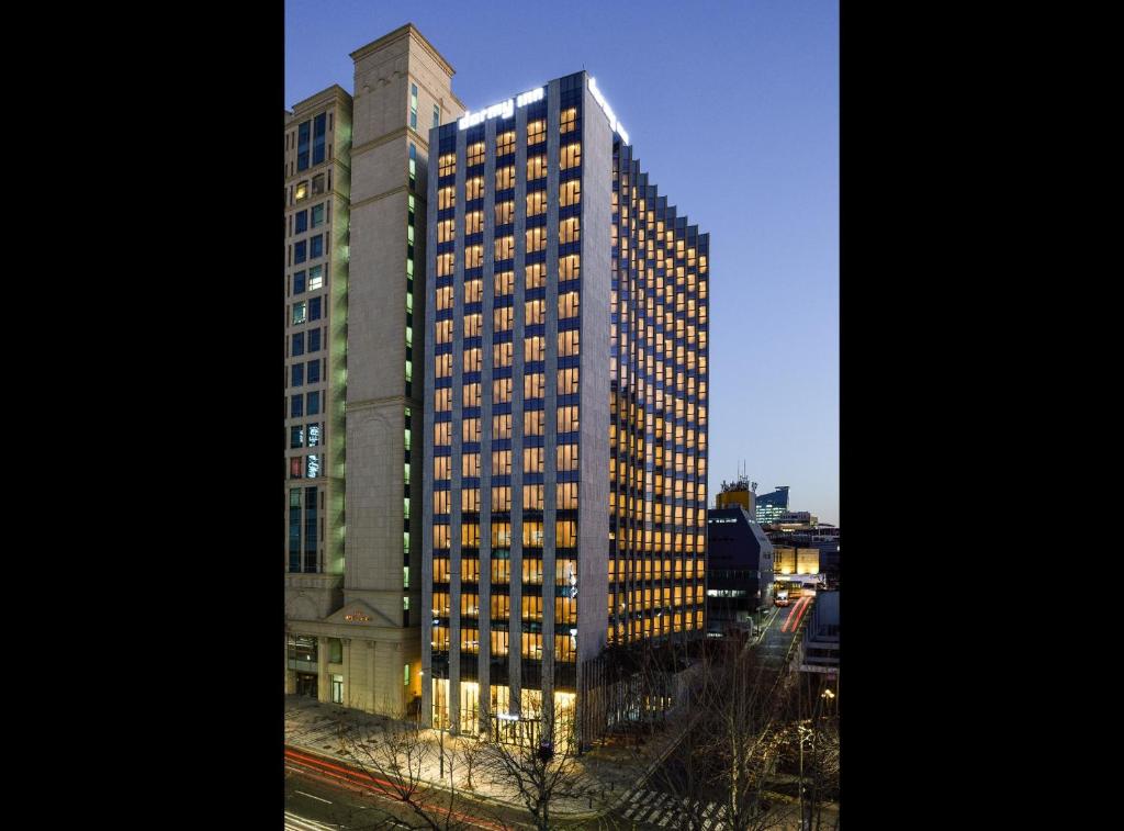 a tall building with many windows in a city at Dormy Inn SEOUL Gangnam in Seoul